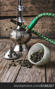 Stylish Arabic hookah. Arab hookah metal and scattered tobacco leaf