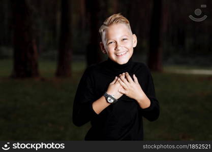 Stylish attractive young guy with a fashionable hairstyle in a trendy black outfit enjoys an outdoor vacation in the park. smiling boy.. Stylish attractive young guy with a fashionable hairstyle in a trendy black outfit enjoys an outdoor vacation in the park. smiling boy