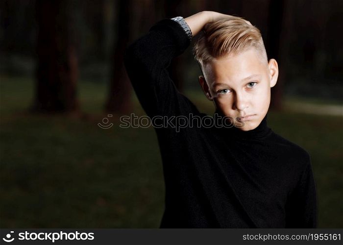 Stylish attractive young guy with a fashionable hairstyle in a trendy black outfit enjoys an outdoor vacation in the park. Stylish attractive young guy with a fashionable hairstyle in a trendy black outfit enjoys an outdoor vacation in the park.