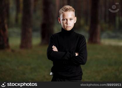 Stylish attractive young guy with a fashionable hairstyle in a trendy black outfit enjoys an outdoor vacation in the park. Stylish attractive young guy with a fashionable hairstyle in a trendy black outfit enjoys an outdoor vacation in the park.