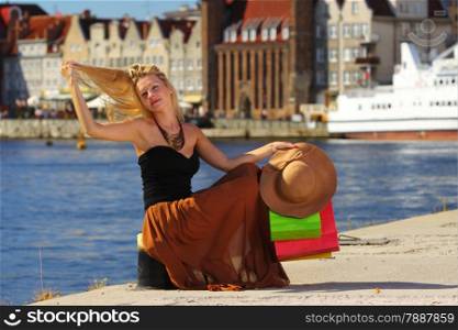 Stylish autumn shopper blonde woman with shopping sale bags in european city, old town Gdansk in the background, Poland Europe