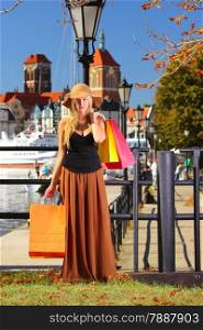Stylish autumn shopper woman in hat with shopping sale bags in european city, old town Gdansk in the background, Poland Europe