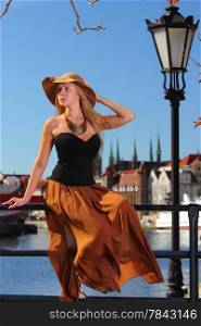 Stylish autumn traveler woman in hat outdoors in european city, old town Gdansk in the background, Poland Europe