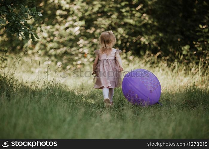 Stylish baby girl 2-5 year old holding big balloon wearing trendy pink dress in meadow. Playful. Birthday party. little girl with a balloon in the park. Stylish baby girl 2-5 year old holding big balloon wearing trendy pink dress in meadow. Playful. little girl with a balloon in the park. Birthday party.