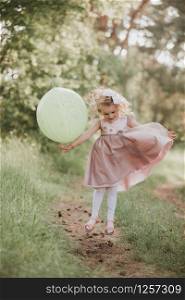 Stylish baby girl 4-5 year old holding big balloon wearing trendy pink dress in meadow. Playful. Birthday party. little girl with a balloon in the park. Stylish baby girl 4-5 year old holding big balloon wearing trendy pink dress in meadow. Playful. little girl with a balloon in the park. Birthday party.
