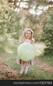 Stylish baby girl 4-5 year old holding big balloon wearing trendy pink dress in meadow. Playful. Birthday party. little girl with a balloon in the park. Stylish baby girl 4-5 year old holding big balloon wearing trendy pink dress in meadow. Playful. little girl with a balloon in the park. Birthday party.