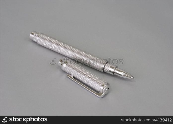 Stylish ballpoint pen of white gold on a grey