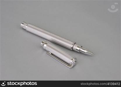 Stylish ballpoint pen of white gold on a grey