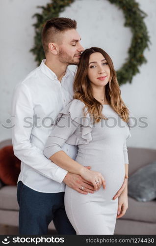 stylish beautiful pregnant couple in love on a Christmas, having a rest on Christmas holidays before the new year. Big pregnant belly.