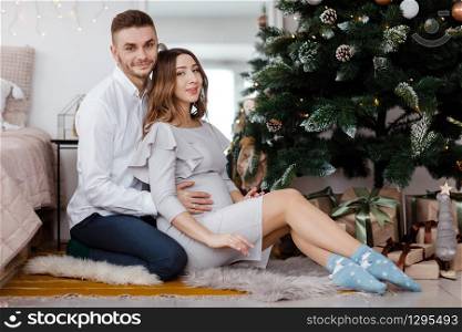 stylish beautiful pregnant couple in love on a Christmas, having a rest on Christmas holidays before the new year. Big pregnant belly.