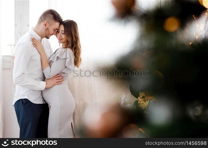 stylish beautiful pregnant couple in love on a Christmas, having a rest on Christmas holidays before the new year. Big pregnant belly. Selective focus. place for text