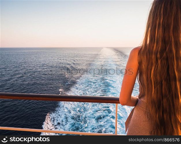 Stylish, beautiful woman on the empty deck of a cruise ship on the background of sea waves, blue sky and sunset. Concept of leisure and travel. Stylish, beautiful woman on the empty deck