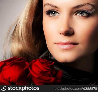 Stylish beautiful young woman holding red roses bouquet, closeup on gorgeous face, tender flowers, blond female over dark background, Caucasian model girl with fresh plant, lady in love concept