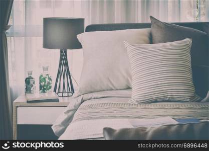 stylish bedroom interior design with brown patterned pillows on bed and decorative table lamp with vintage style effect