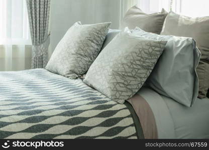 stylish bedroom interior design with patterned pillows on bed and decorative table lamp.