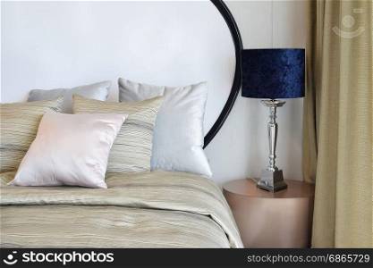 stylish bedroom interior design with pillows on bed and decorative table lamp.