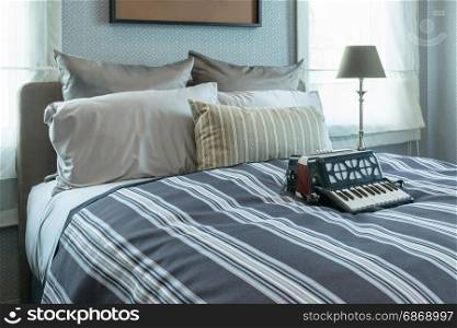 stylish bedroom interior design with striped pillows and decorative accordion on bed