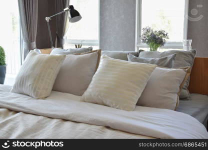 stylish bedroom interior design with white striped pillows on bed and decorative table lamp.