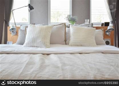 stylish bedroom interior design with white striped pillows on bed and decorative table lamp.