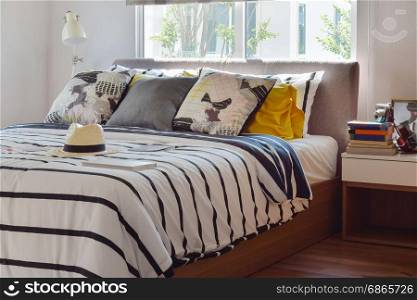 stylish bedroom interior with black and white patterned pillows on bed and decorative table lamp.