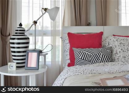 stylish bedroom interior with flower pattern pillows and decorative table lamp