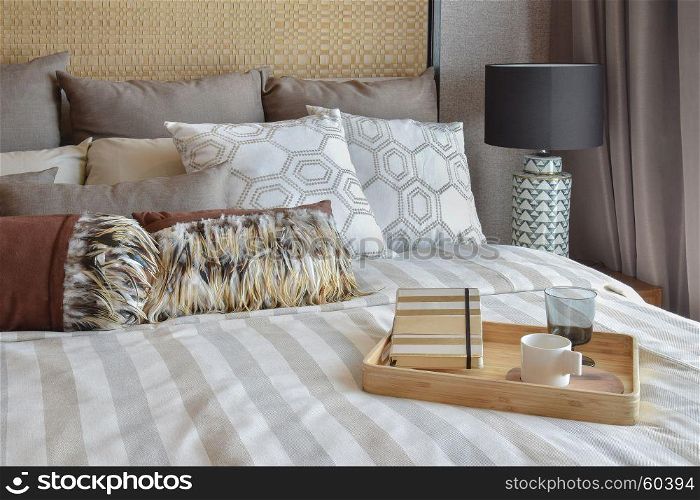 stylish bedroom interior with striped pillows and decorative tea set on bed