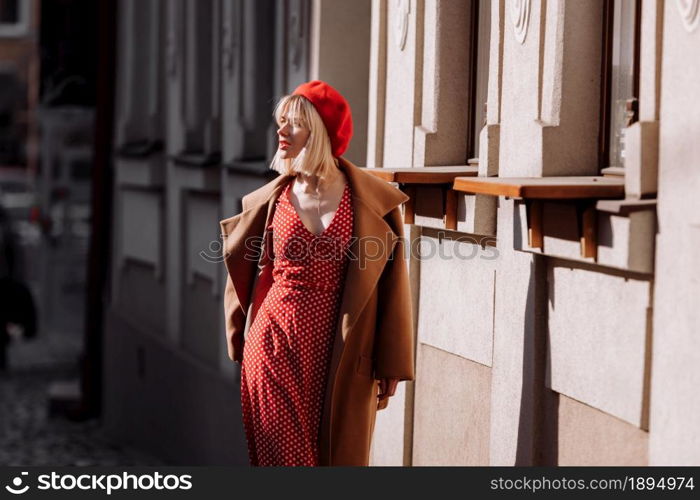 stylish blonde in a red dress in the spring city. Beautiful girl in red dress posing on city streets. Stunning young woman walking in the city. stylish blonde in a red dress in the spring city. Beautiful girl in red dress posing on city streets. Stunning young woman walking in the city.