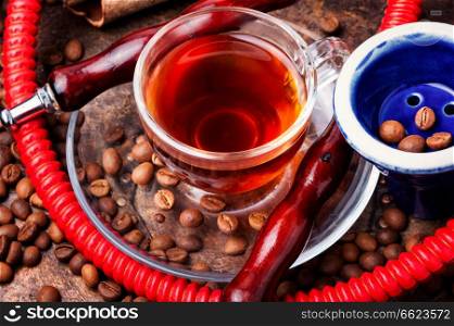 Stylish coffee cup with coffee and hookah mouthpiece.Arabian shisha and coffee. Hookah with aroma coffee
