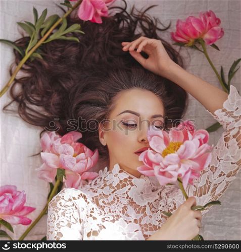 Stylish fashion photo of beautiful young woman lies among peonies. Holidays and Events. Valentine&rsquo;s Day. Spring blossom. Summer season