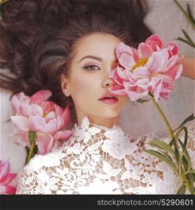 Stylish fashion photo of beautiful young woman lies among peonies. Holidays and Events. Valentine&rsquo;s Day. Spring blossom. Summer season