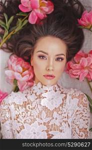 Stylish fashion photo of beautiful young woman lies among peonies. Holidays and Events. Valentine?s Day. Spring blossom. Summer season