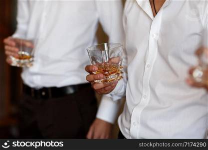 stylish friends businessmen in suits toasting with glasses of whiskey indoors, closeup. groom&rsquo;s morning.. stylish friends businessmen in suits toasting with glasses of whiskey indoors, closeup. groom&rsquo;s morning