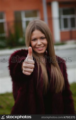 Stylish girl with long hair and fur coat saying Ok in the street