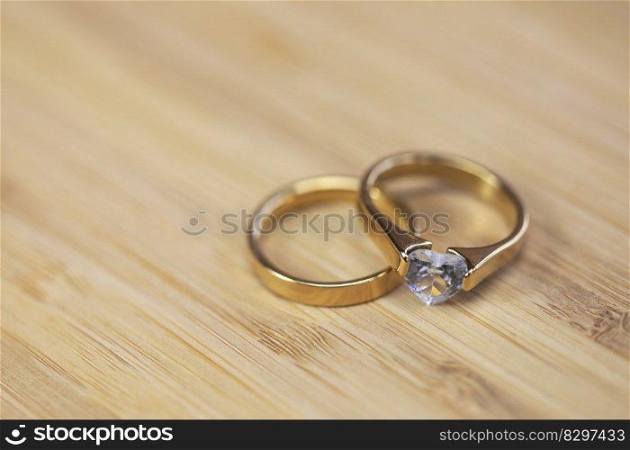 Stylish gold wedding rings with diamond on wooden table background. Bride and groom. Engagement. Luxury marriage and wedding accessory concept love. Stylish gold wedding rings with diamond on wooden table background. Bride and groom. Engagement. Luxury marriage and wedding accessory concept.