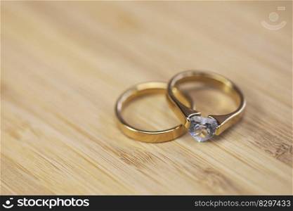 Stylish gold wedding rings with diamond on wooden table background. Bride and groom. Engagement. Luxury marriage and wedding accessory concept love. Stylish gold wedding rings with diamond on wooden table background. Bride and groom. Engagement. Luxury marriage and wedding accessory concept.