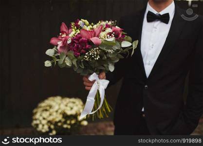 Stylish groom are holding bridal bouquet. Wedding bouquet in man hands.. Stylish groom are holding bridal bouquet. Wedding bouquet in man hands