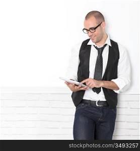 Stylish handsome guy leaning on wall with touchpad