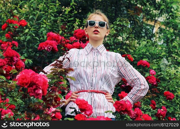 Stylish hipster girl in trendy glasses. Glamorous photo shoot in a chic outdoor garden. Photo toned style Instagram filters