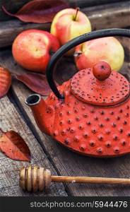 Stylish kettle and an apple. Red trendy retro teapot on background of autumn harvest apples