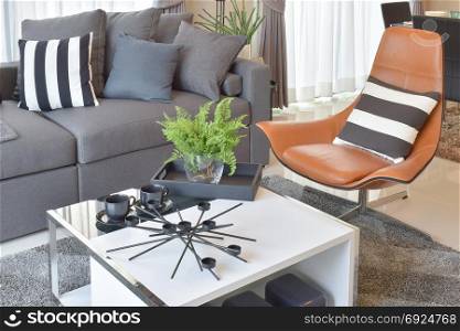 stylish living room design with grey pillows on comfortable sofa and brown leather chair