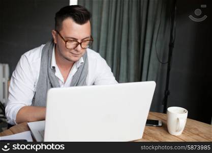 Stylish man using laptop in startup office