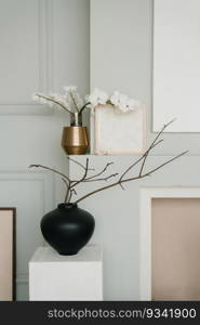 Stylish minimalist Scandinavian living room decor in gray. Branches of spring trees in vases in the room