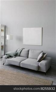 Stylish minimalistic interior of the living room in gray. Sofa with plaid, floor l&, beige carpet and mockup white frame on the wall