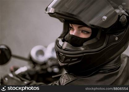 Stylish motorcyclist woman in helmet and leather jacket sitting on black motorcycle. Female driver outdoors on nature background. Trip, cafe racers, speed, freedom concept. High quality photo. Stylish motorcyclist woman in helmet and leather jacket sitting on black motorcycle. Female driver outdoors on nature background. Trip, cafe racers, speed, freedom concept.