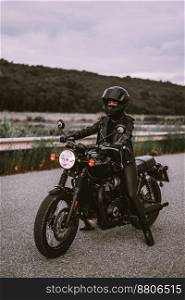 Stylish motorcyclist woman in helmet and leather jacket sitting on vintage motorcycle. Female driver outdoors on nature background. Trip, cafe racers, speed, freedom concept. High quality photo. Stylish motorcyclist woman in helmet and leather jacket sitting on vintage motorcycle. Female driver outdoors on nature background. Trip, cafe racers, speed, freedom concept.