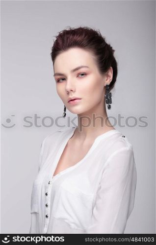 Stylish portrait of a woman. Fashion. A white blouse. Large earrings.