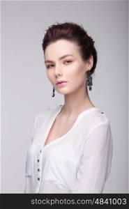 Stylish portrait of a woman. Fashion. A white blouse. Large earrings.