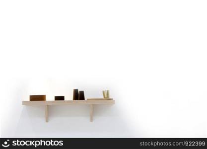 Stylish shelf with various dishware hanging on white wall. Decorative vases on wooden shelf