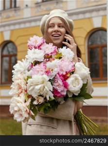 stylish smiley woman holding bouquet flowers outdoors spring talking phone
