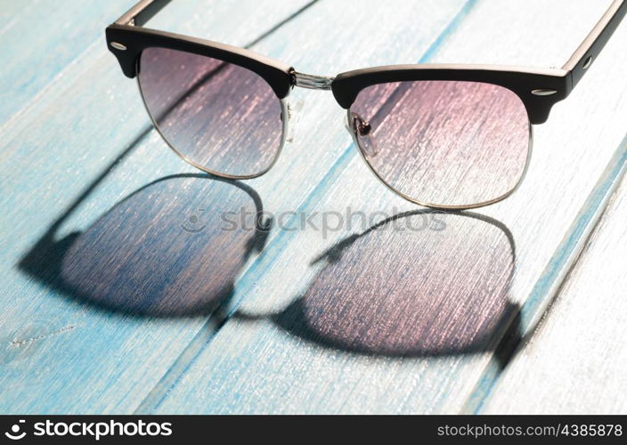 stylish sunglasses on table. stylish sunglasses on blue wooden table with sunlight